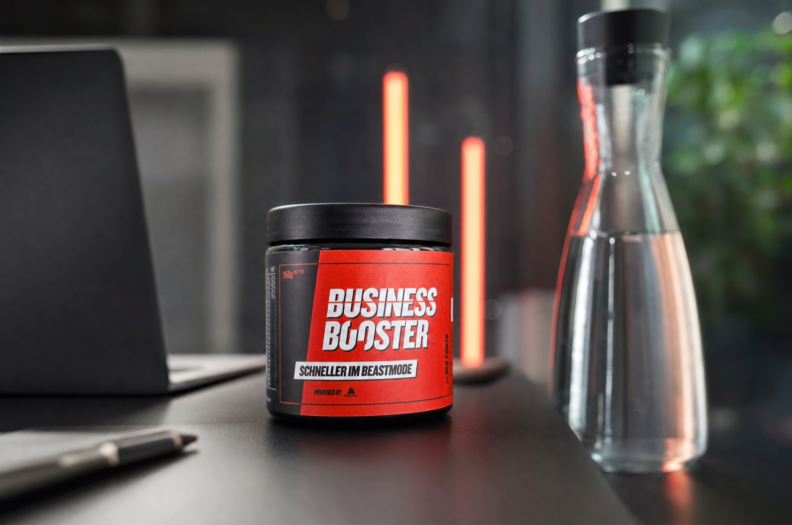 Business Booster Red Power Dose auf dem Schreibtisch neben Laptop und Wasserkaraffe